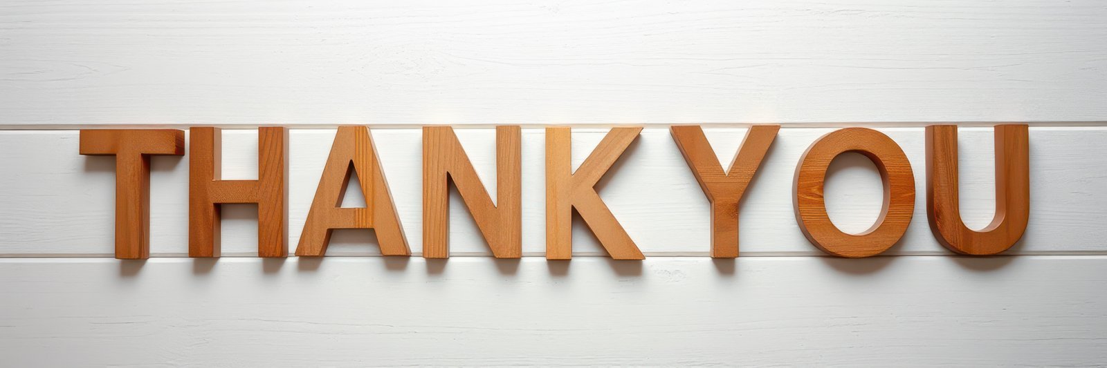 Wooden letters spell out a message of gratitude displayed against a simple white background, emphasizing appreciation in a modern setting